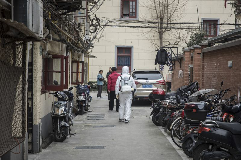A man in a protective suit disinfects a residential neighborhood in Shanghai, Feb. 5